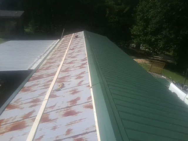 Old rusted panels beside newly installed green metal roofing — Wind Damage Roof Repair by Roofing Brothers in Brush