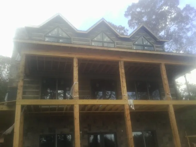Dormers and porch framing on a large log home under construction — Roof Coating work by our crew in Brush