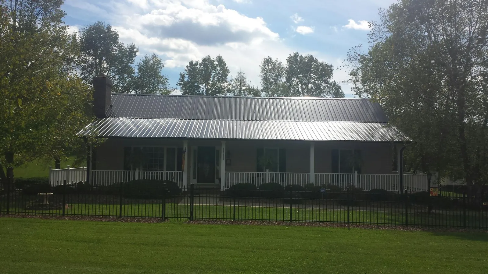 Gray metal roof on a brick ranch with a full width front porch in Brush