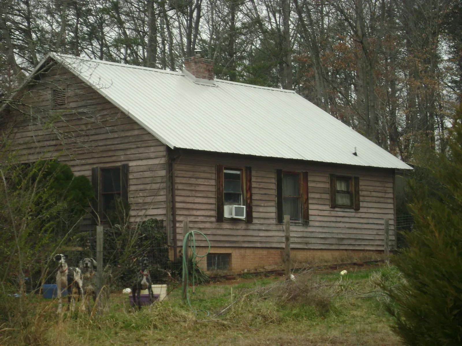 White metal roof on an old wood sided farmhouse, from a Metal Roof Installation job in Brush