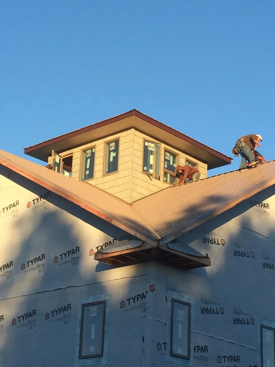 Roofers working around a rooftop cupola on a new metal roof at sunset — Roof Waterproofing in Brush by Roofing Brothers